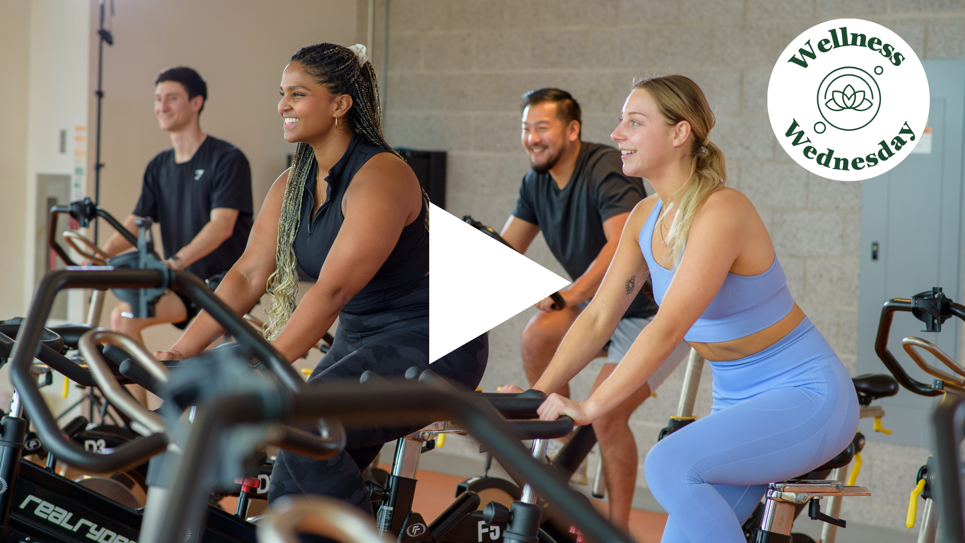 4 individuals on exercycles smiling